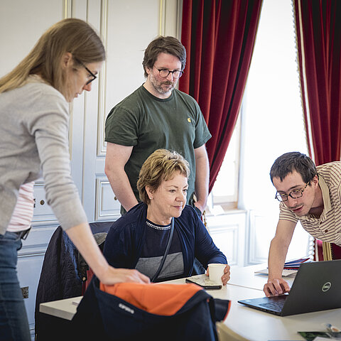 Un groupe de trois personnes de la Bibliothèque d’Yverdon-les-Bains participent à la formation à la chaîne de l’accessibilité du projet pilote Yverdon culture accessible. Les personnes montrent le site internet de la Bibliothèque sur un ordinateur à Monique Richoz qui est membre de la commission consultative d’Yverdon culture accessible et ancienne directrice de Pro Infirmis Vaud. 